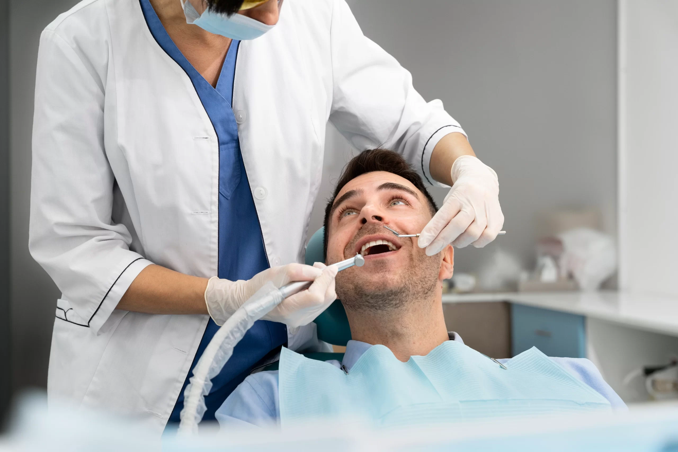 Dentist performing a dental check-up on a patient seated in a clinic chair and identifying potential reasons for root canal treatment.