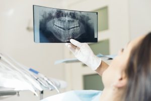 A dentist examines an x-ray image of a patient's teeth